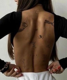 the back of a woman with tattoos on her upper and lower back, showing various symbols