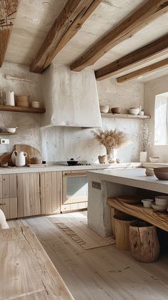 a rustic kitchen with wood floors and white walls is pictured in this image, there are wooden shelves on the wall