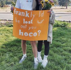 two people standing in the grass holding a sign