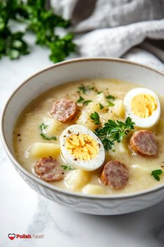 a white bowl filled with soup topped with hard boiled eggs and meatballs, garnished with parsley