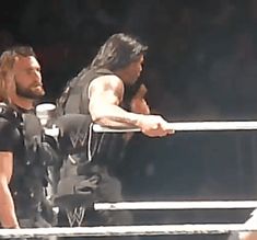 two men standing next to each other on top of a wrestling ring