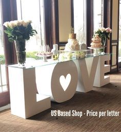 a table that has some cakes on it and flowers in front of the letters love