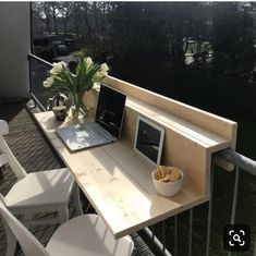 a laptop computer sitting on top of a wooden table next to a bowl of fruit