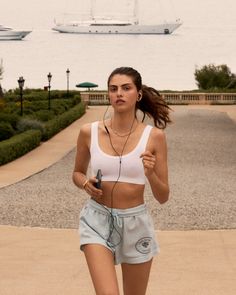 a woman running on the sidewalk with headphones in her ears and an ocean view behind her