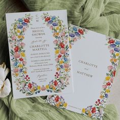 the wedding stationery is laid out on top of the green blanket with flowers and leaves