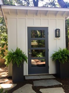 a small white shed with two planters on the front and one in the back