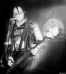 a black and white photo of a man playing bass guitar in front of a microphone