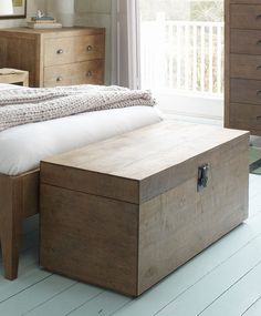 a bed sitting next to a wooden chest on top of a hard wood floor