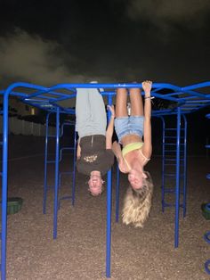 two young children are playing on a blue metal play structure at night with dark clouds in the background