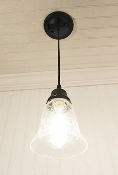 a light fixture hanging from the ceiling in a room with white walls and wood paneling