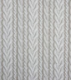 white knitted fabric textured with braids and lines, closeup view from above