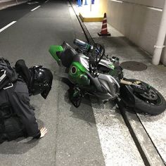 a motorcycle that is laying down on the ground next to a man in black jacket