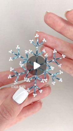 someone is holding a snowflake ornament that looks like it has been made out of beads