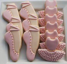 decorated cookies in the shape of ballet shoes on a white plate with pink icing