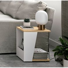 a table with a lamp on it next to a couch and a potted plant