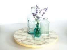 two vases with flowers in them sitting on a marble tray, one is empty