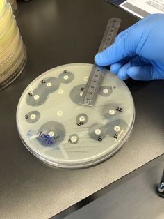 a person in blue gloves is holding a test tube and measuring it with a ruler