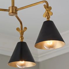 two black and gold lamps hanging from a ceiling fixture in a room with white walls