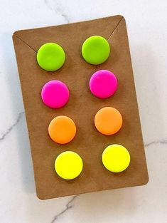 four different colored buttons sitting on top of a piece of brown paper next to a white marble counter