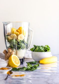 a blender filled with fruit and vegetables on top of a marble counter next to other ingredients