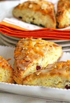 some scones are sitting on a plate with orange and white napkins next to them