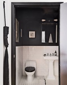 a white toilet sitting next to a black and white sink in a bathroom under a mirror