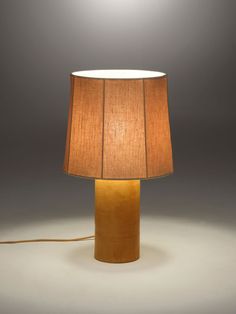 a table lamp with a brown shade on it and a white light in the background