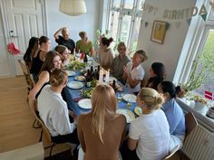 a group of people sitting around a table with plates and wine bottles on it,