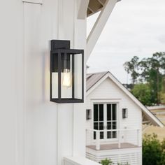 a light that is on the side of a wall next to a house and trees