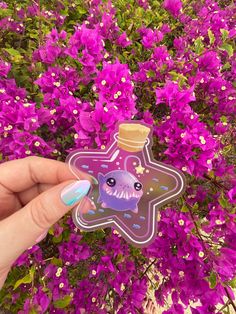 a hand holding a sticker with purple flowers in the background and a star on it