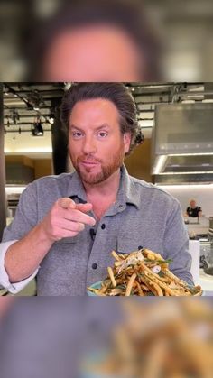 a man holding a fork and looking at the camera with food in front of him