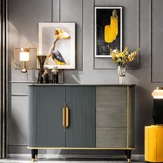 a grey and yellow sideboard with two pictures on the wall