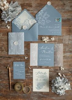 the wedding stationery is laid out on a wooden table