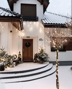 a white house with christmas lights on the front door and steps leading up to it