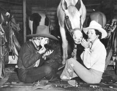 black and white photograph of two women sitting on the ground next to a horse