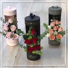 three black boxes with flowers and greenery in them