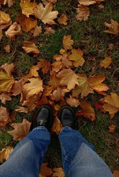 a person standing in the grass with their feet up and leaves on the ground behind them