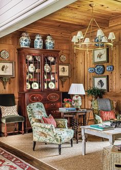 a living room filled with furniture and wooden paneled walls, along with pictures on the wall