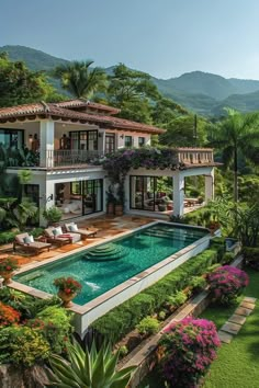 an aerial view of a house with a swimming pool in the foreground and lush greenery surrounding it