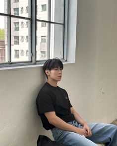 a young man sitting on top of a window sill in front of a building