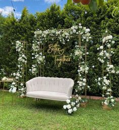 an outdoor seating area with white flowers and greenery on the side, along with a gold framed sign that says better together