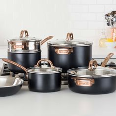 black pots and pans are sitting on the stove top with copper handles in this kitchen