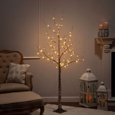 a lighted tree in a living room next to a chair