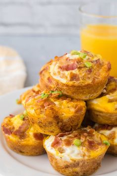 breakfast muffins piled on top of each other with orange juice in the background