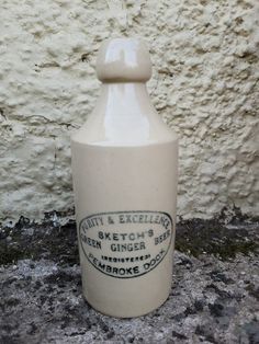 a white bottle sitting in front of a wall