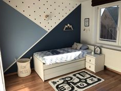 a bedroom with blue and white walls, wooden floors and a bed in the corner