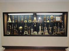 a display case filled with lots of trophy cups and trophies on top of wooden floors