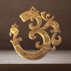 an intricately designed golden metal object sitting on top of a wooden table