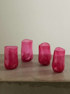 five pink glass cups sitting on top of a table