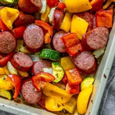 sausage, peppers and zucchini in a casserole dish on a towel